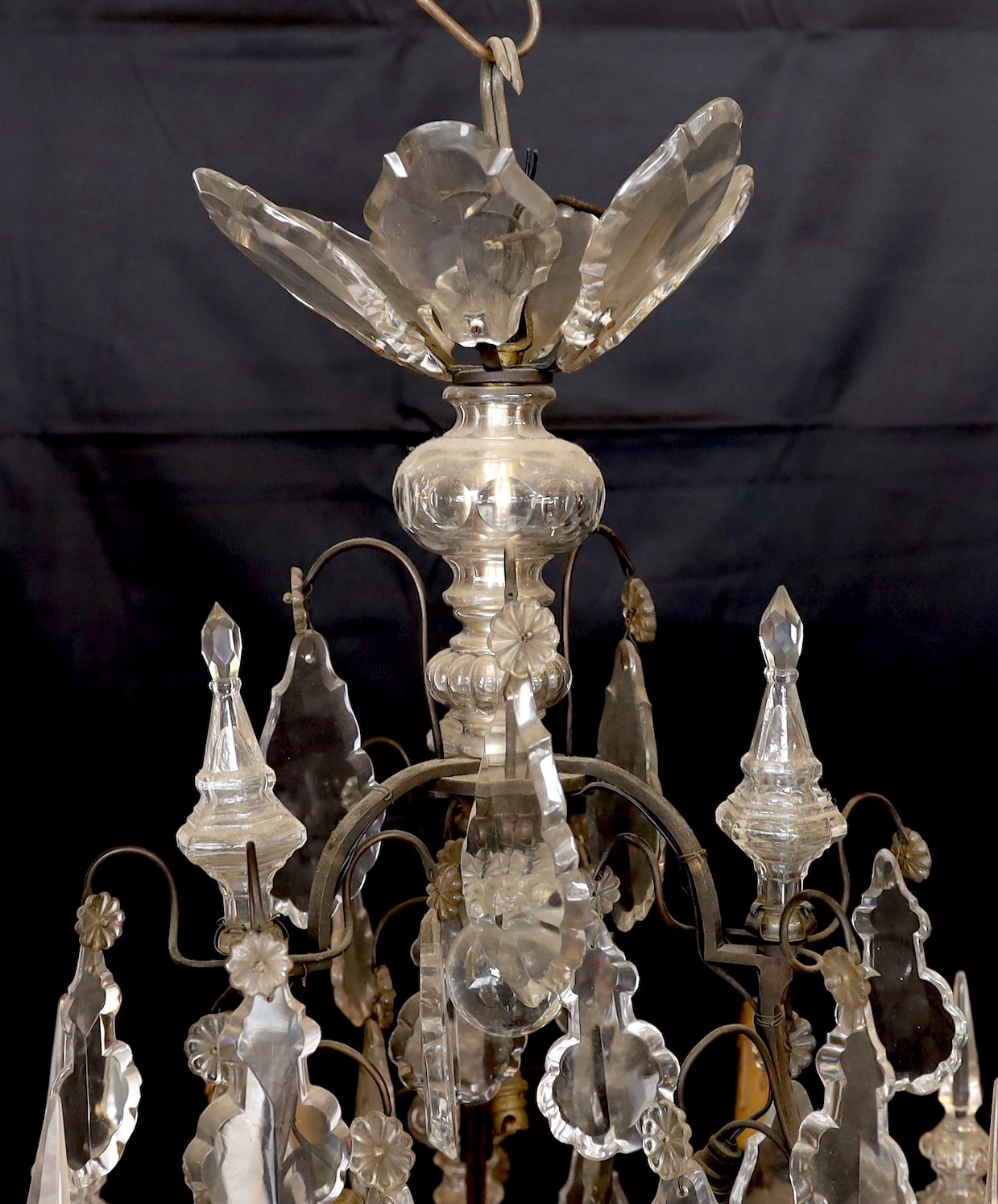 An early 20th century French bronze and cut glass six light chandelier, of particularly ornate design with spear finials, lozenge shaped drops and flower head motifs, height 101cm. width 60cm